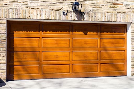 Classic wood garage door with raised panel design and warm woodgrain finish.