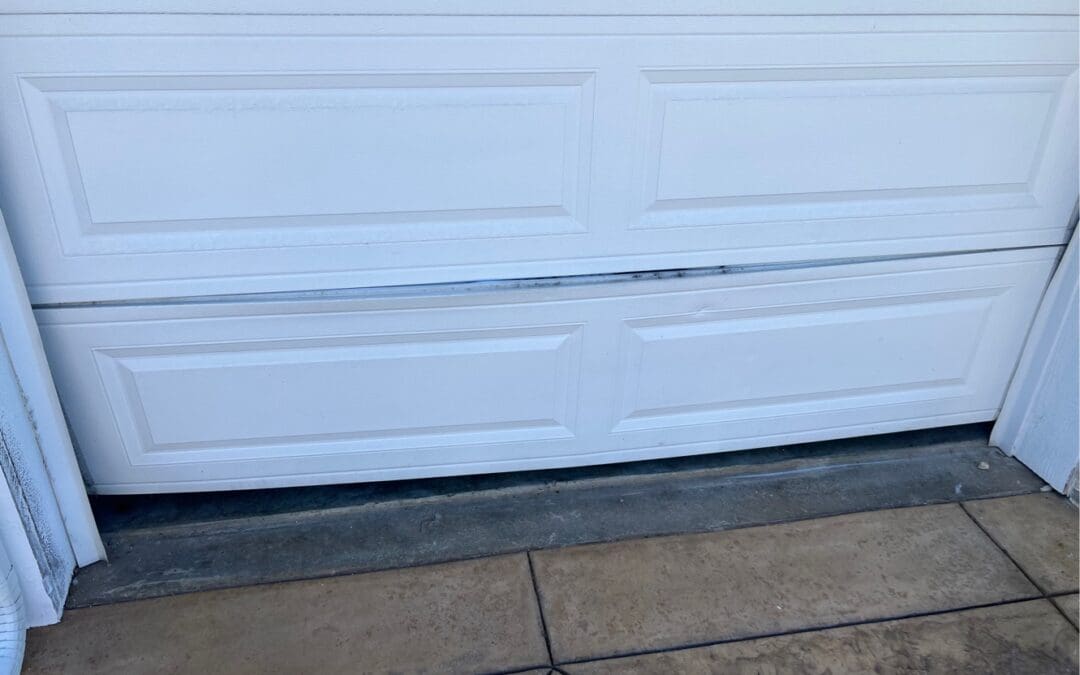 Damaged white garage door panels and high-tension springs, illustrating risks of DIY repair.