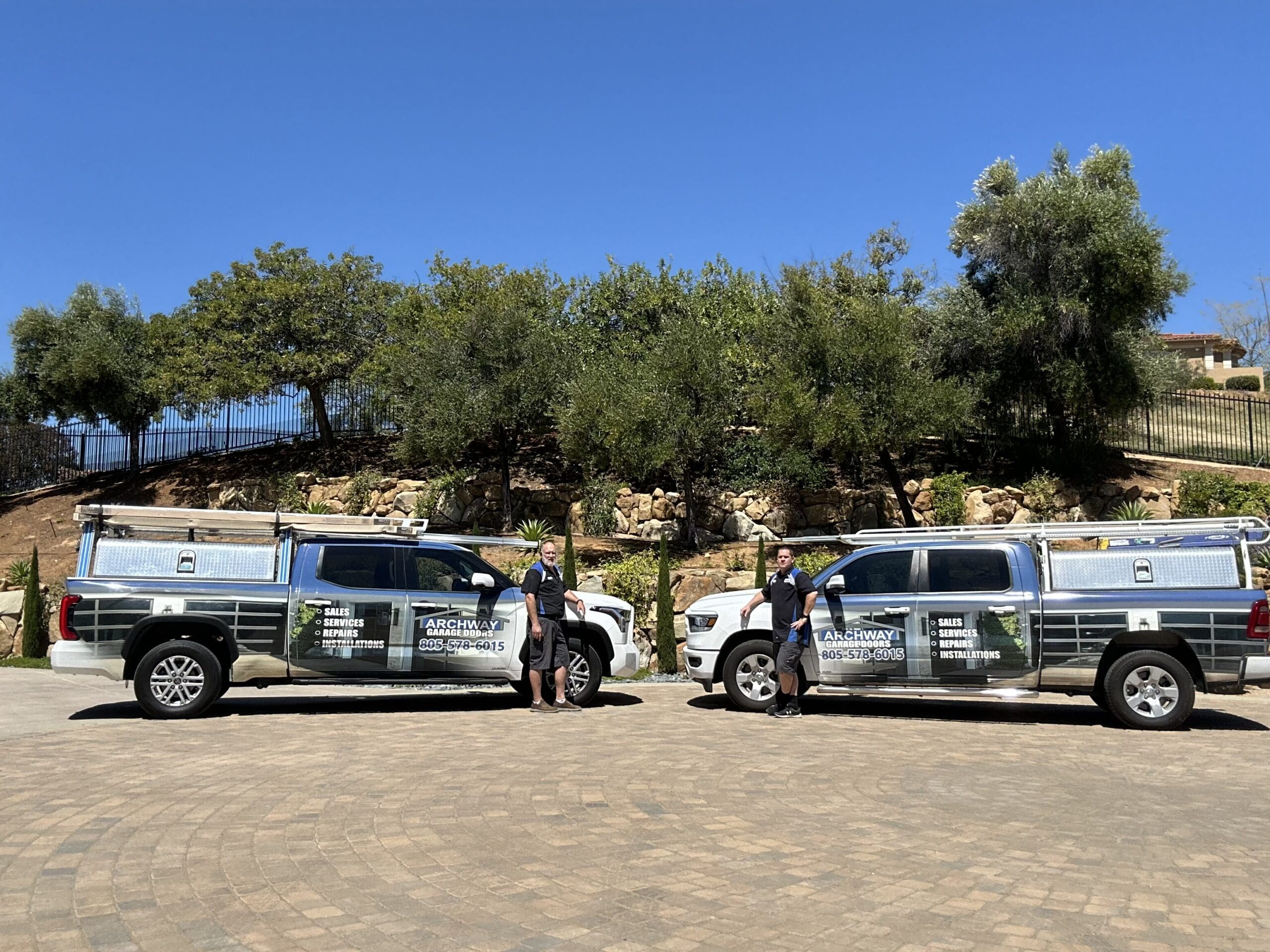 Archway Garage Doors owners and team standing beside company trucks, sidemount garage door opener installation services.